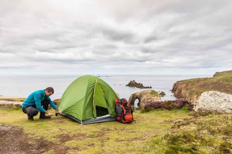 using a camping hammer to peg out tent